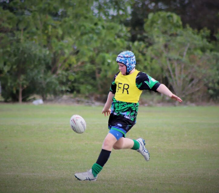 Young athlete demonstrates perfect form, preparing to kick the ball with power and precision at Proserpine Whitsunday Junior Rugby League